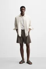 Bermuda regular fit negra confeccionada en tejido de lino. Cintura elástica ajustable con cordón y pliegues frontales. Bolsillos frontales y detalle de bolsillos traseros de plastrón.