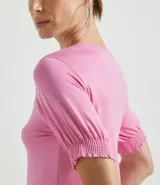 Blusa de viscolycra color rosado, con cuello redondo y mangas cortas abullonadas con puños de lastex.