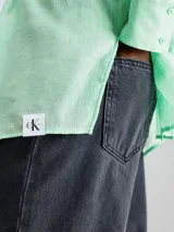 Camisa verde menta de rayón arrugado, corte regular, cuello en punta, manga larga con puños abotonados y espalda dividida con detalle anudado.