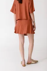 Minifalda color ladrillo con rayas verticales finas y botones dorados en el lateral.