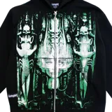 Campera negra de felpa con cierre metálico y capucha. Diseño estampado con motivos de arte biomecánico en tonos verdes.