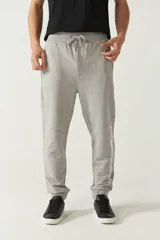 Pantalón de jogging gris melange de felpa, con puños ajustados, cintura ajustable con cordón y bolsillos laterales. Presenta logo de goma en la pierna izquierda.