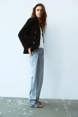 Blazer color blanco hueso, de corte entallado y doble botonadura dorada.