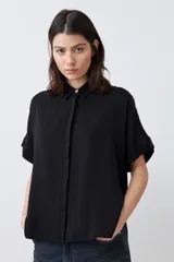 Camisa negra de manga corta con cuello clásico y cierre frontal con botones.