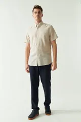 Camisa de manga corta color beige claro, confeccionada en lino y algodón, con cuello abotonado, bolsillo en el pecho y logo bordado. Corte semi slim.