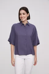 Camisa color blanco, de corte holgado con manga corta y botones frontales.