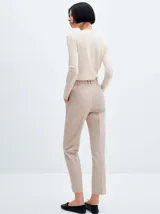 Pantalón de vestir color beige, de corte recto y entallado, con pinzas delanteras, bolsillos laterales y cierre invisible.