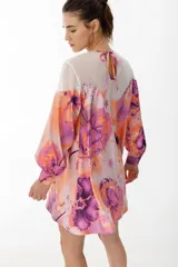 Vestido corto de satén con maxi estampado en tonos azules y morados, con mangas largas abullonadas y lazo en la espalda.