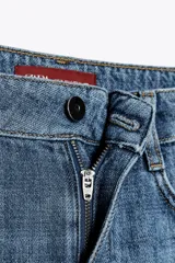 Pantalón de jean azul de corte wide leg, tiro alto, con cinco bolsillos y cierre frontal con cremallera y botón.