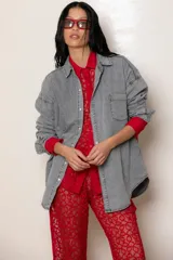 Camisa de jean celeste de corte oversize, con cuello clásico, cierre frontal con botones, bolsillo en el pecho y mangas largas con puños abotonados. Detalle de bordado en el puño.