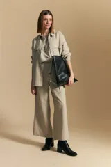 Camisa de manga larga color blanco hueso con finas rayas verticales en color oscuro. Presenta cuello camisero, botones frontales y dos bolsillos superpuestos en el pecho.