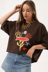 Remerón oversize de algodón color chocolate con estampado de motivos marinos en tonos rojo, amarillo, azul y blanco.