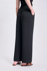 Pantalón negro de corte palazzo, con cintura alta y textura arrugada.