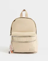 Mochila color beige de tela deportiva con dos bolsillos frontales con cierre, correas regulables, manija superior, doble cierre superior y tag de goma con el logo de la marca.