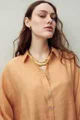 Camisa celeste de calce relajado con cuello clásico, mangas tres cuartos amplias y botones nacarados.