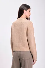 Sweater color beige de punto con cuello alto y mangas ranglan largas. Tejido acanalado vertical.