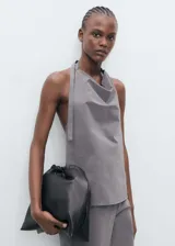 Top gris con cuello drapeado y espalda descubierta, con tiras finas para atar en el cuello y la espalda.