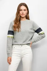 Buzo gris con mangas raglán y bandas horizontales en azul, blanco y verde en los brazos.