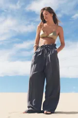 Pantalón gris de tejido fluido, tiro alto con cintura tipo paper bag, bolsillos laterales y cinturón lazada en el mismo tejido.