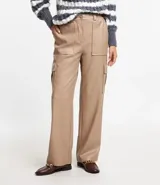 Pantalón recto color beige de material sintético, con trabillas en la cintura, cierre delantero, cintura elástica en la espalda y bolsillos laterales tipo cargo.