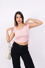 Remera negra de corte crop con escote redondo y mangas cortas. Presenta cordones ajustables en los laterales.