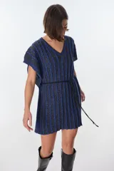 Vestido corto de tejido de punto con cuello V y mangas cortas, con diseño de rayas verticales en tonos azul oscuro y negro, con hilos de lurex que le dan brillo. Se ajusta a la cintura con un lazo fino negro.