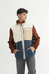 Campera de sherpa doble faz en tonos marrón, beige y azul, con cierre frontal y bolsillos laterales.