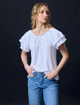 Blusa blanca texturada de poliéster, rayón y elastano, con mangas cortas con volados en capas y aplique de puntilla.