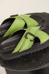 Sandalias planas color beige con tiras cruzadas y hebilla decorativa.