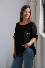 Blusa negra de lino con cuello redondo y mangas 3/4 con detalle de botón. Presenta un bolsillo en el pecho con bordado de lentejuelas y cuentas.