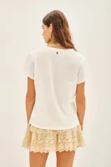 Remera blanca de algodón con bordado frontal de mostacillas metálicas formando la palabra "Smile".