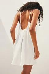 Vestido corto blanco de muselina de algodón suave, corte holgado, con breteles finos ajustables, escote recto y espalda redondeada.