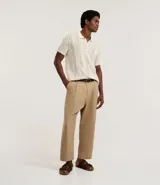 Pantalón masculino estilo sastre, corte balloon (holgado con volumen y talle alto), color beige. Presenta pliegues frontales y cierre tradicional.