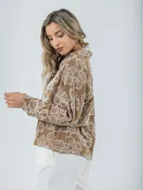 Blusa color crudo con bordados florales, cuello camisero y mangas largas.