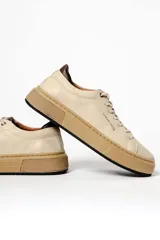 Zapatillas urbanas de cuero negro con cordones, suela blanca y detalles en marrón.