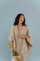 Ruana de lana merino color beige, tejida a mano con detalles de brillos y flecos.