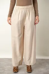 Pantalón palazzo de viscosa y lino color beige claro satinado, con cintura elastizada y bolsillos laterales.