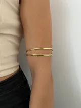 Brazalete hecho a mano en bronce dorado, con diseño minimalista y estructura doble.