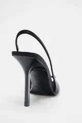 Zapato de tacón destalonado color negro con efecto satinado, punta fina, abertura delantera y tira trasera elástica. Tacón alto fino.