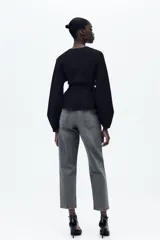 Pantalón de jean gris oscuro, de corte mom fit, tiro alto y largo tobillero. Cuenta con cinco bolsillos, cierre frontal con cremallera y botón.