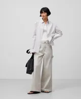 Pantalón palazzo de denim crudo para mujer, de tiro alto, con cierre de botón metálico, trabillas, bolsillos laterales y traseros, costura lateral desplazada al delantero de la pierna, pespuntes decorativos a contraste y parche logotipado en la espalda.