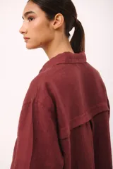 Vestido camisero corto color borgoña de lino italiano, con cuello camisero, manga larga, cierre frontal con botones y dos bolsillos de parche en el pecho con bordado de cerezas.