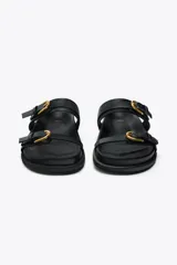 Sandalias planas negras con dos tiras ajustables con hebillas doradas y punta redonda.