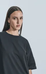 Remera negra de corte crop y calce oversize, con hombros caídos y cuello redondo.