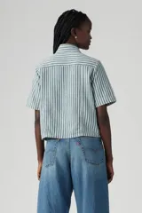 Camisa de denim a rayas verticales verdes y blancas, con cuello clásico, manga corta y cierre frontal con botones.