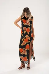 Vestido midi negro con estampado de flores naranjas y beige, espalda descubierta con tres botones en forma de flor, tajo lateral y flecos en el ruedo.