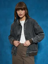 Campera de jean celeste con corte bomber, cierre frontal con botones metálicos, cuello redondo y puños y cintura acanalados.