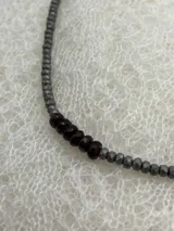 Collar corto de cuentas facetadas de hematita gris con detalles de cuentas de granate rojo oscuro.