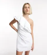 Vestido corto blanco de sastrería, confeccionado en algodón, con escote asimétrico de un solo hombro y volados.