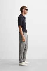 Pantalón negro de corte slim fit, confeccionado en tejido elástico. Cuenta con cintura elástica, bolsillos frontales y traseros de vivo. Cierre frontal con cremallera y botón.